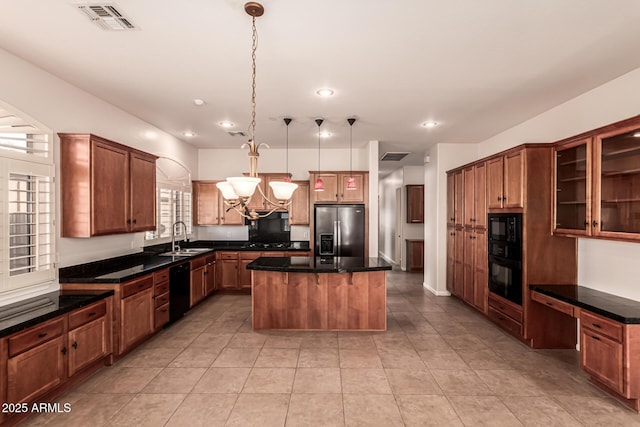 kitchen featuring light tile patterned flooring, a chandelier, a center island, visible vents, and black appliances
