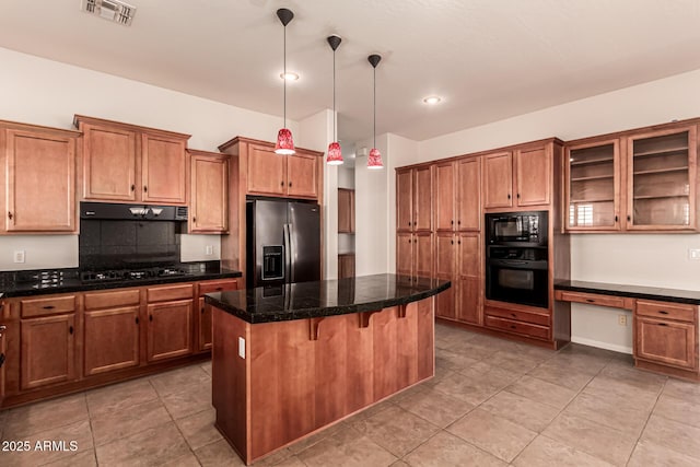 kitchen with a kitchen island, visible vents, brown cabinets, black appliances, and tile counters