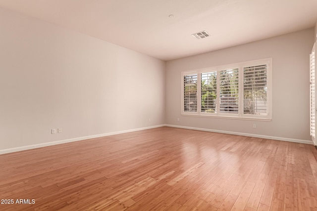 empty room with baseboards, visible vents, and light wood-type flooring