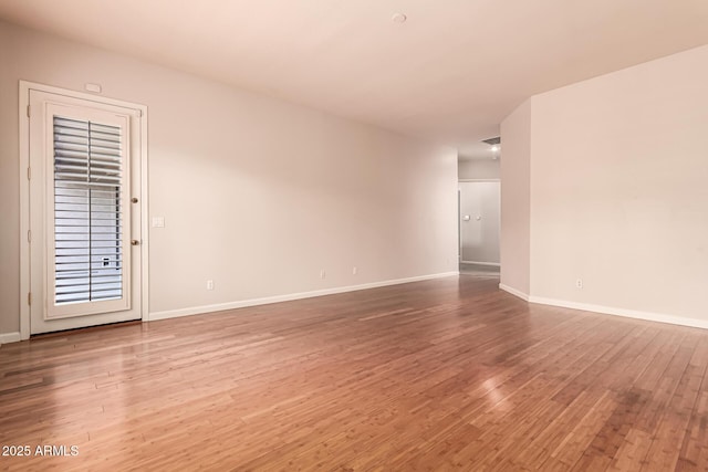 spare room featuring baseboards and wood finished floors
