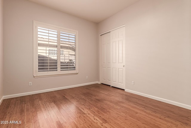 unfurnished bedroom with baseboards, a closet, and hardwood / wood-style floors