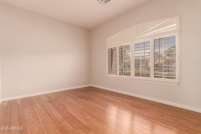 spare room featuring baseboards and light wood finished floors