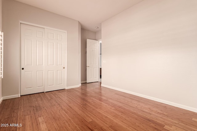 unfurnished bedroom with light wood-style floors, baseboards, and a closet