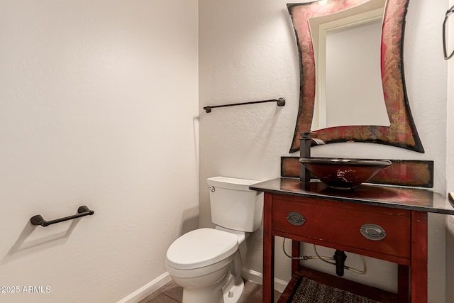 bathroom featuring toilet, baseboards, and vanity