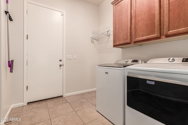 laundry room with washing machine and clothes dryer, baseboards, light tile patterned floors, and cabinet space