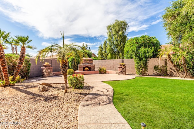 view of yard featuring an outdoor stone fireplace, a fenced backyard, and a patio area