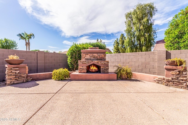 view of patio / terrace with fence and an outdoor stone fireplace