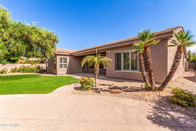 ranch-style home with a patio, a front lawn, stucco siding, and fence