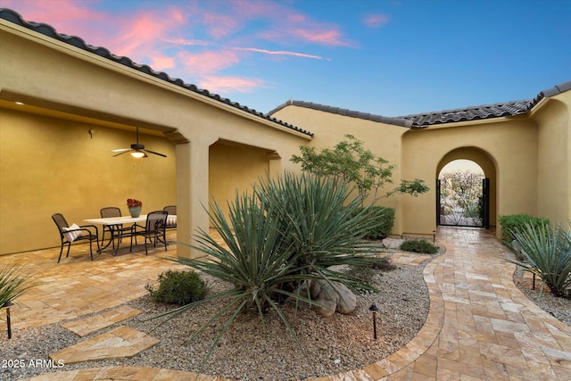 exterior entry at dusk featuring a patio and ceiling fan