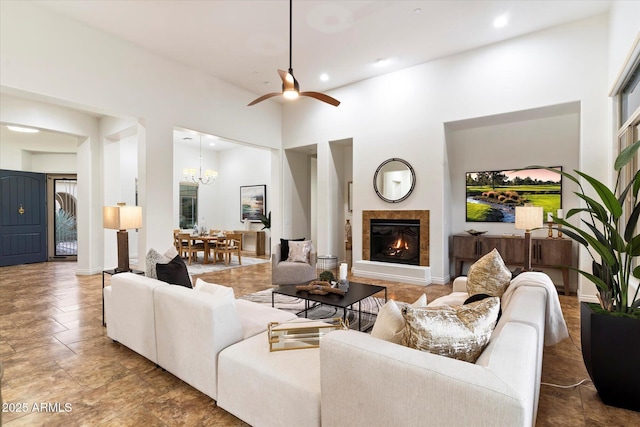 living room with ceiling fan with notable chandelier and a high ceiling