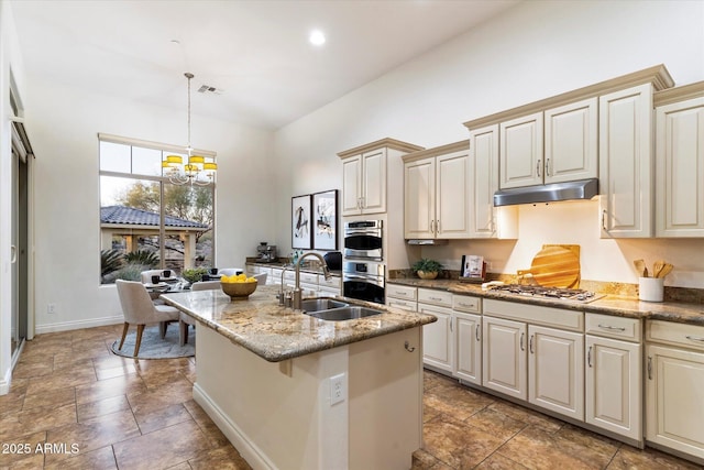 kitchen with pendant lighting, sink, stainless steel appliances, a center island with sink, and cream cabinetry