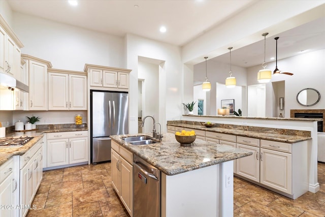 kitchen featuring appliances with stainless steel finishes, pendant lighting, sink, kitchen peninsula, and a center island with sink