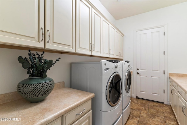 clothes washing area featuring cabinets and washer and clothes dryer