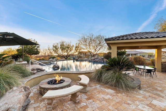 view of patio featuring an outdoor fire pit and a fenced in pool