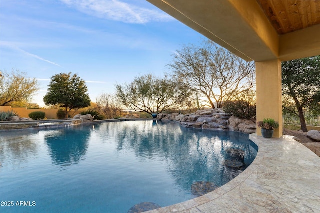 pool at dusk featuring a patio