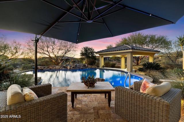 pool at dusk with a gazebo, a water view, and an outdoor hangout area