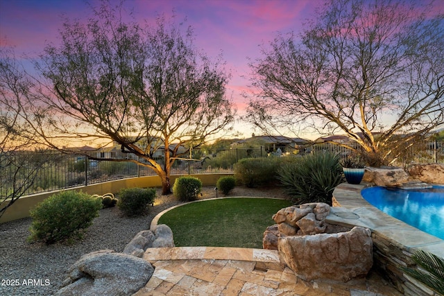 yard at dusk with a fenced in pool