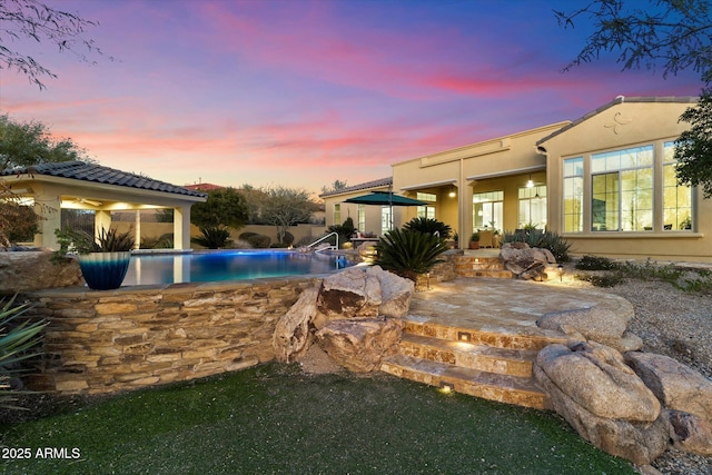 pool at dusk featuring a patio area