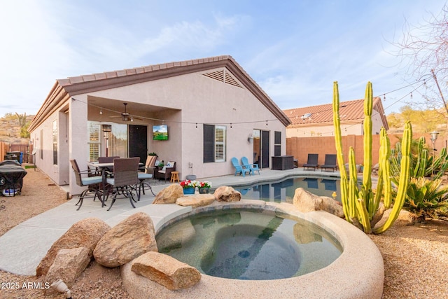 rear view of house featuring ceiling fan, a pool with hot tub, and a patio