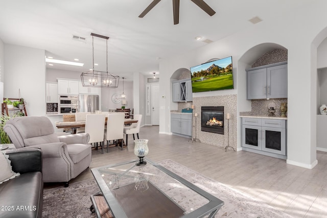 living room with ceiling fan, light hardwood / wood-style floors, and a tile fireplace