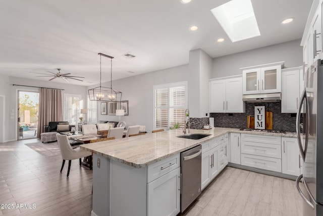 kitchen featuring appliances with stainless steel finishes, kitchen peninsula, sink, and white cabinets