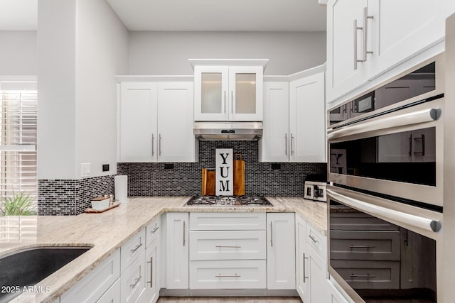 kitchen with backsplash, appliances with stainless steel finishes, light stone counters, and white cabinets