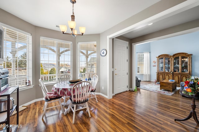 dining space with an inviting chandelier, baseboards, and wood finished floors