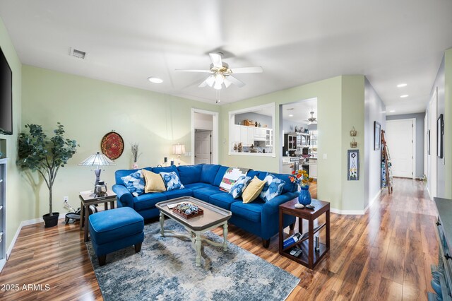 living area with baseboards, visible vents, a ceiling fan, and wood finished floors