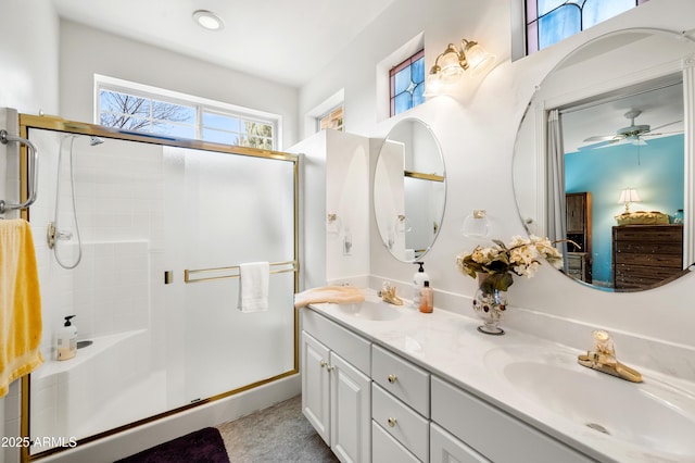 full bath featuring a shower stall, double vanity, a sink, and a ceiling fan