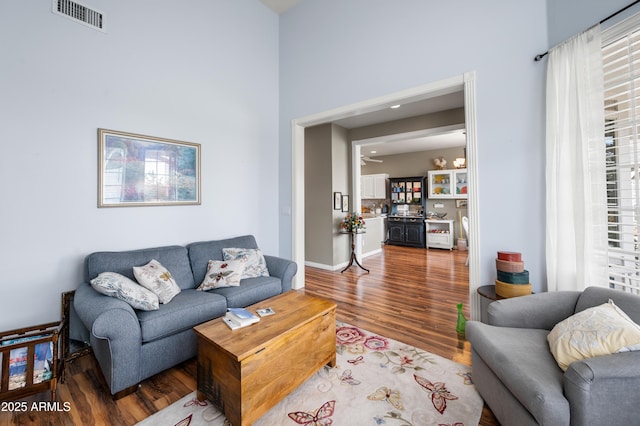 living room with wood finished floors, baseboards, and visible vents