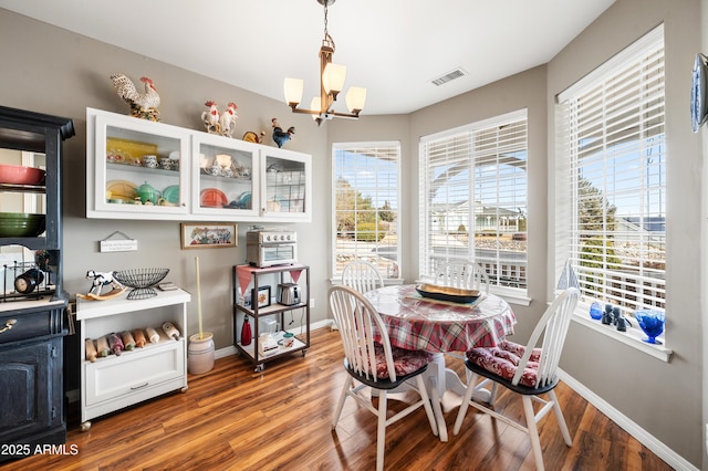 dining area with baseboards, visible vents, wood finished floors, and a notable chandelier