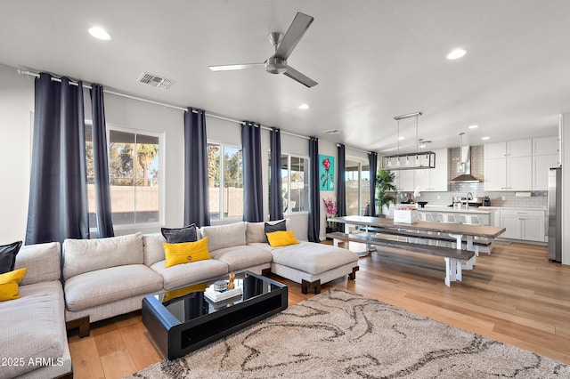 living room with ceiling fan, sink, and light hardwood / wood-style floors