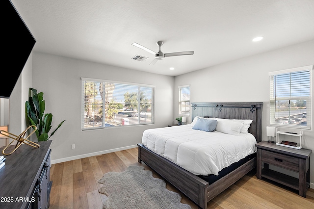 bedroom with ceiling fan, light hardwood / wood-style floors, and multiple windows