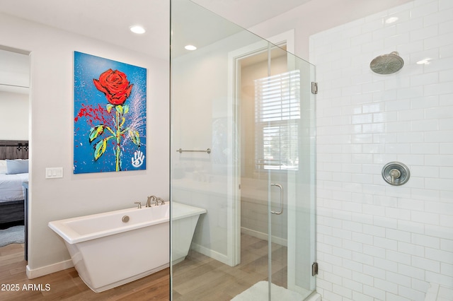 bathroom featuring plus walk in shower and hardwood / wood-style flooring