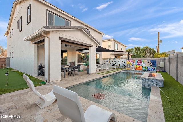 view of swimming pool with ceiling fan, a patio area, and a fire pit