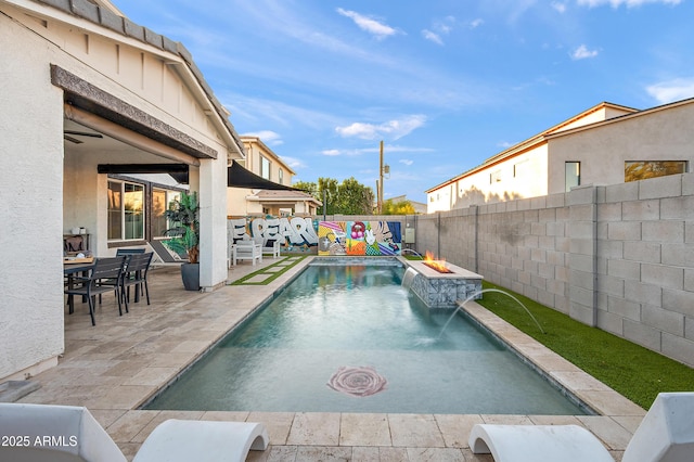 view of pool with pool water feature, a patio area, and an outdoor fire pit