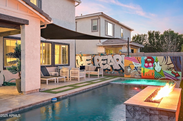 pool at dusk featuring a patio area and an outdoor living space with a fire pit