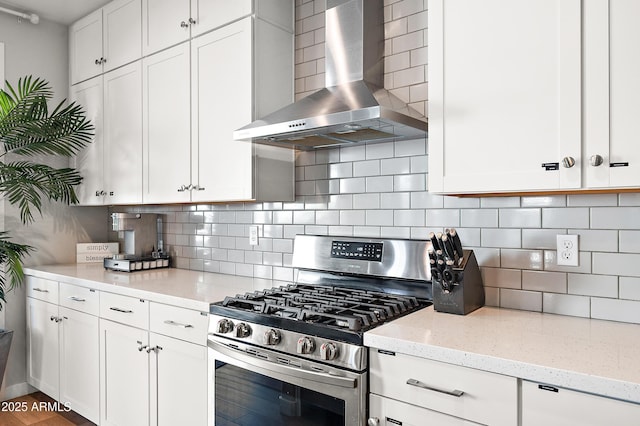 kitchen featuring white cabinets, stainless steel gas stove, tasteful backsplash, and wall chimney range hood