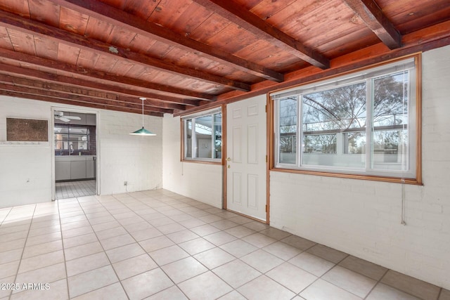 empty room with light tile patterned floors, brick wall, beamed ceiling, and wooden ceiling