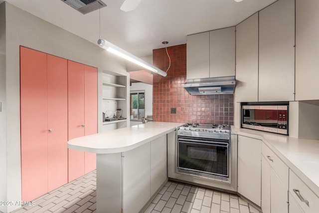 kitchen featuring stainless steel appliances, wall chimney range hood, a peninsula, and light countertops