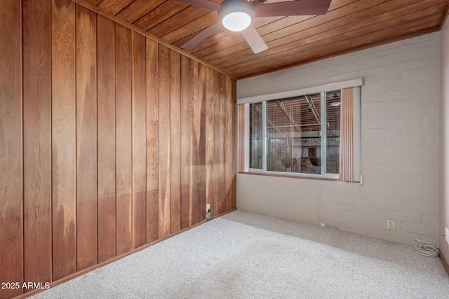 carpeted empty room featuring wooden ceiling, ceiling fan, and wooden walls