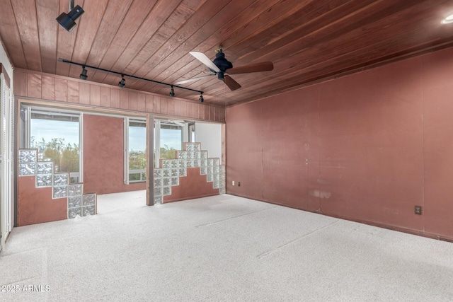 carpeted spare room featuring a ceiling fan, wood ceiling, track lighting, and stairs