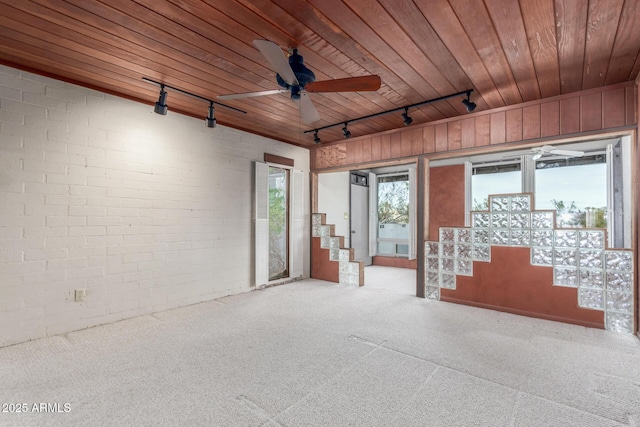 unfurnished room with a ceiling fan, carpet, wooden ceiling, and brick wall