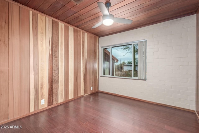 unfurnished room with wood ceiling, ceiling fan, brick wall, wood finished floors, and baseboards