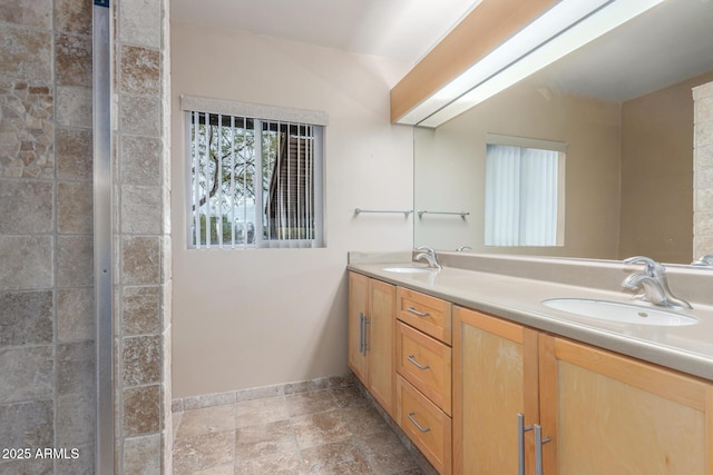 bathroom with double vanity, stone finish flooring, a sink, and baseboards