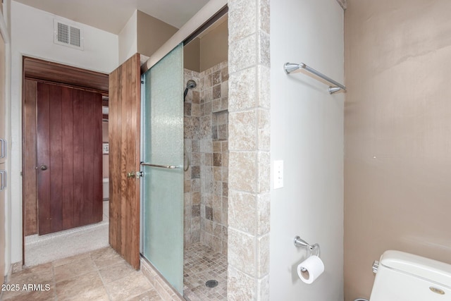 bathroom with toilet, a stall shower, and visible vents