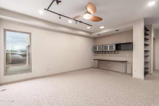 unfurnished living room featuring carpet, rail lighting, ceiling fan, and baseboards