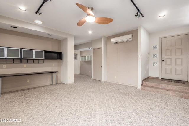 unfurnished living room featuring baseboards, ceiling fan, rail lighting, an AC wall unit, and carpet floors