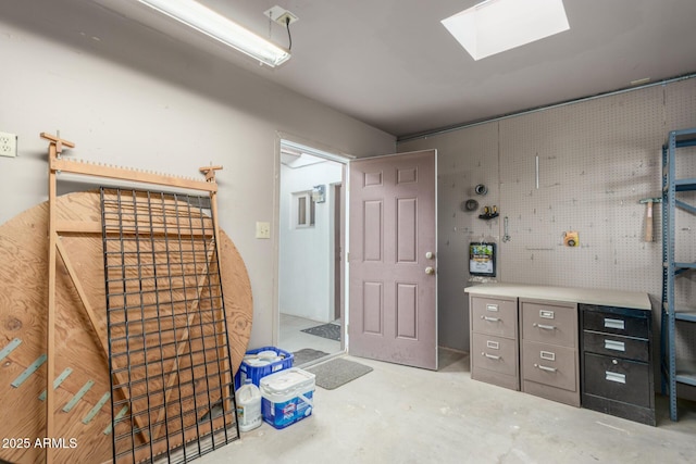 misc room with a skylight, unfinished concrete flooring, and a workshop area