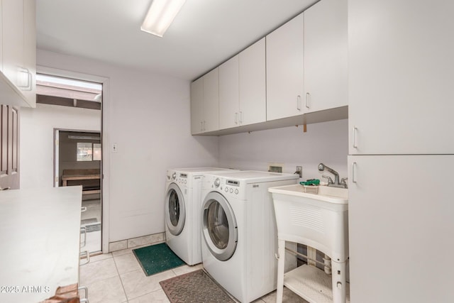 laundry area featuring washer and dryer, cabinet space, and light tile patterned flooring